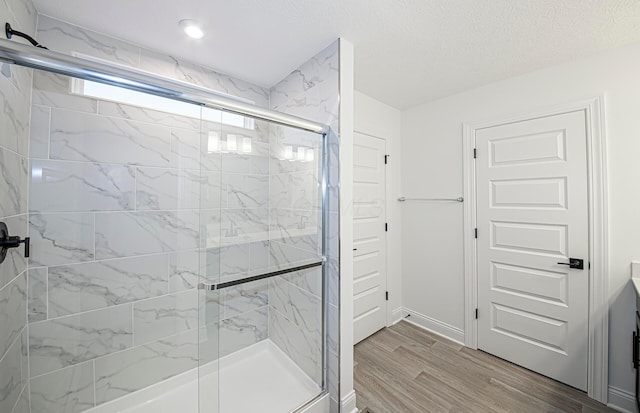 bathroom with hardwood / wood-style floors, vanity, a shower with door, and a textured ceiling