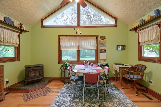 dining space with plenty of natural light, a wood stove, and light hardwood / wood-style flooring