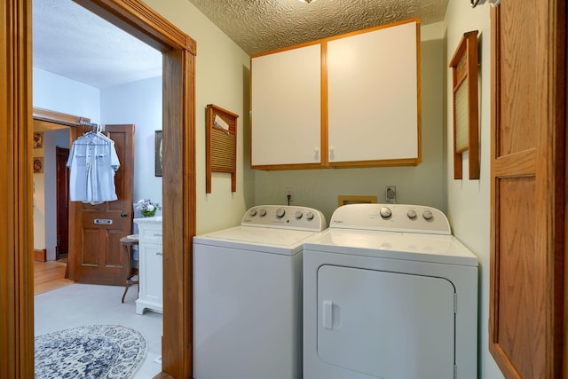 washroom with washer and dryer, light tile patterned flooring, cabinets, and a textured ceiling