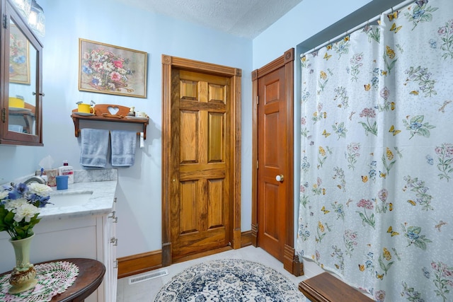 bathroom with tile patterned floors, vanity, curtained shower, and a textured ceiling