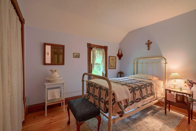 bedroom with light hardwood / wood-style flooring and vaulted ceiling