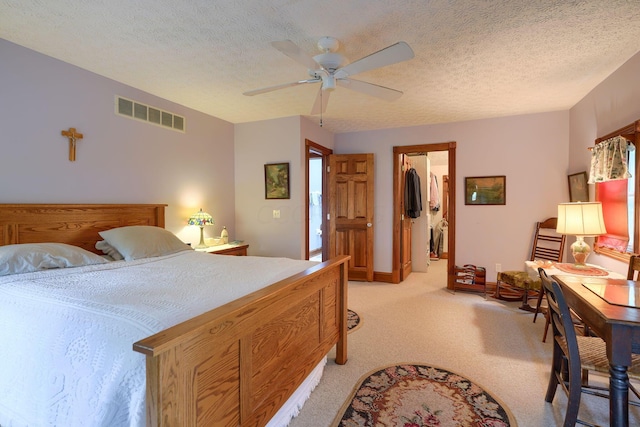 carpeted bedroom with ceiling fan, a walk in closet, a textured ceiling, and a closet