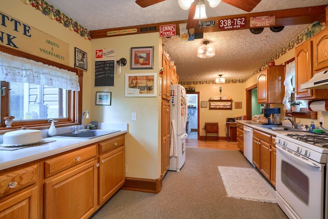 kitchen with sink, white appliances, a textured ceiling, and light carpet