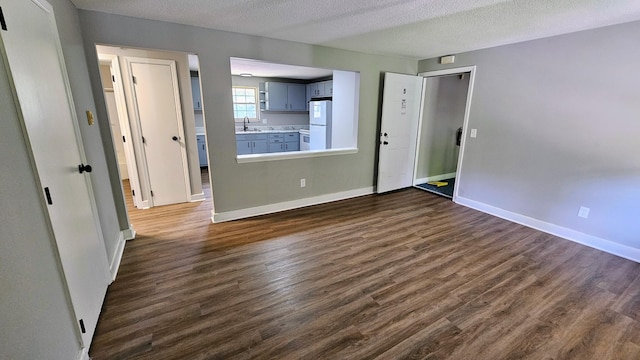 unfurnished living room with a textured ceiling, dark hardwood / wood-style flooring, and sink