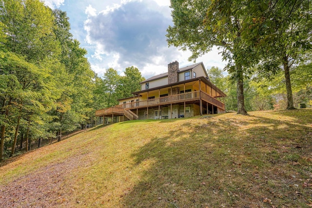 rear view of property featuring a deck and a lawn