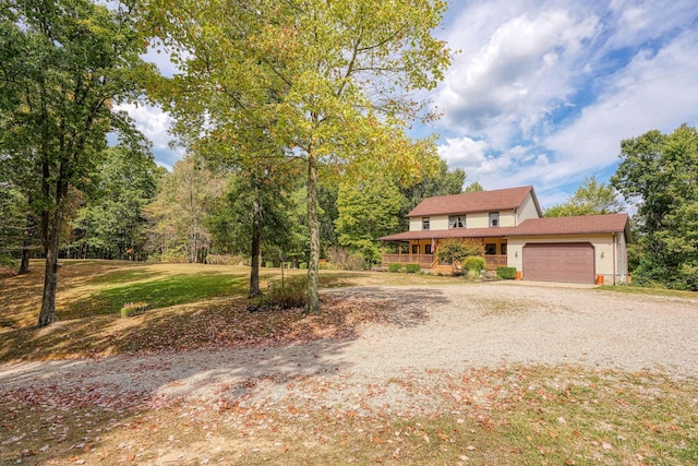 view of front of house with covered porch, a garage, and a front lawn