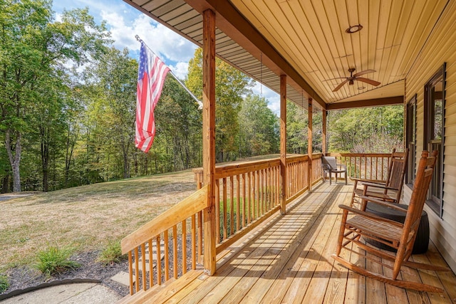 wooden terrace with ceiling fan, a yard, and a porch