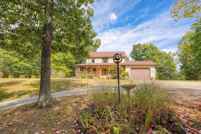 view of front of property with a porch, a garage, and a front lawn