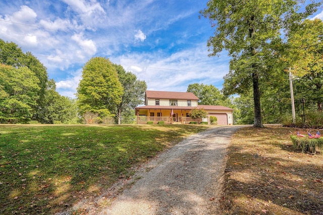 view of front of home with covered porch, a front yard, and a garage