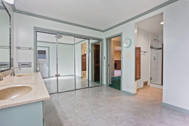 bathroom with vanity, a shower with shower door, and ornamental molding