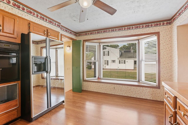 kitchen with ceiling fan, crown molding, light hardwood / wood-style floors, a textured ceiling, and black appliances