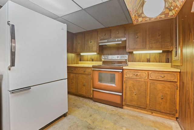 kitchen with a paneled ceiling, white refrigerator, wood walls, and range with electric cooktop