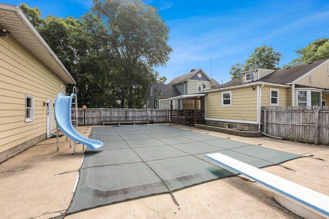 view of swimming pool featuring a diving board, a patio, and a water slide