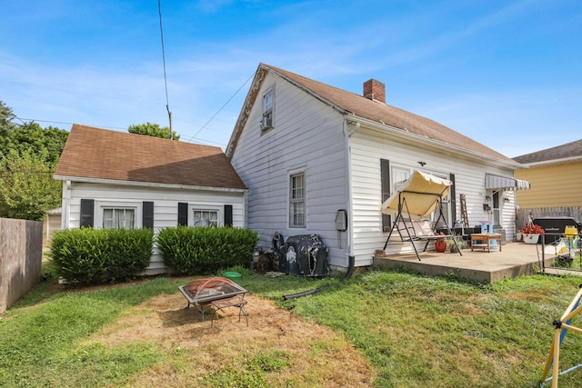 rear view of property with a yard, an outdoor fire pit, and a patio