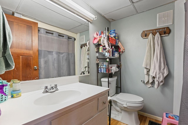 bathroom with a paneled ceiling, a shower with curtain, vanity, hardwood / wood-style flooring, and toilet