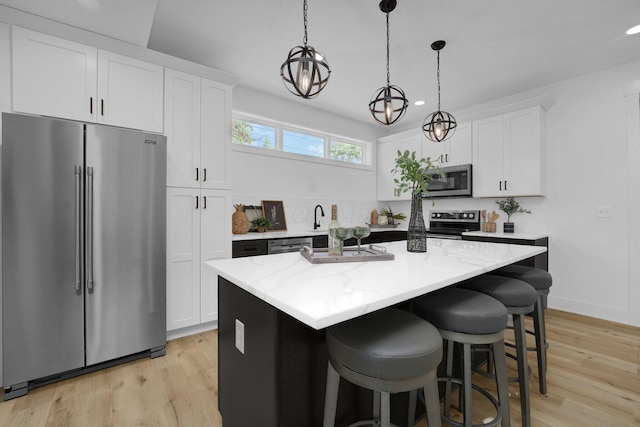 kitchen featuring white cabinets, decorative light fixtures, a kitchen island, and appliances with stainless steel finishes