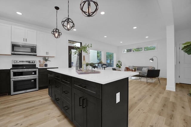 kitchen featuring hanging light fixtures, a kitchen island, light hardwood / wood-style flooring, white cabinets, and appliances with stainless steel finishes