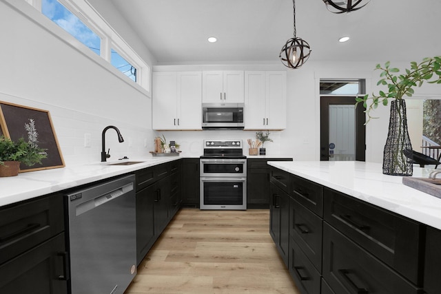 kitchen with sink, stainless steel appliances, light stone counters, light hardwood / wood-style floors, and white cabinets