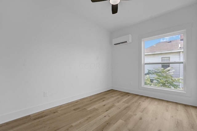 unfurnished room with a wall mounted air conditioner, light hardwood / wood-style flooring, and ceiling fan