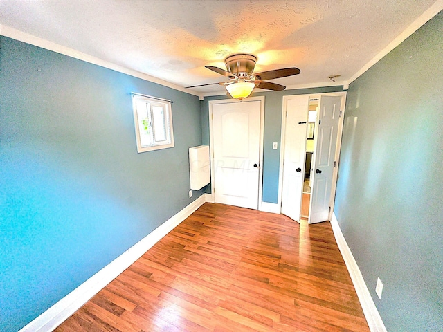 empty room with crown molding, light hardwood / wood-style flooring, ceiling fan, and a textured ceiling