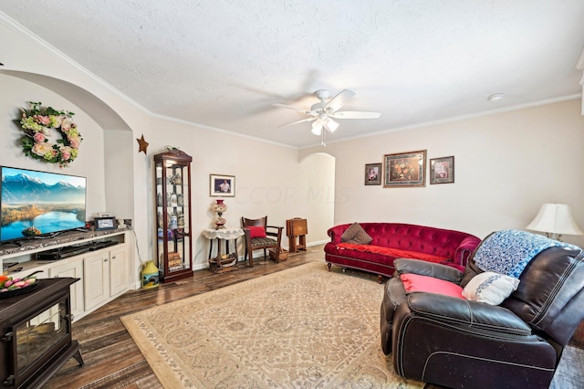 living room featuring ceiling fan, dark hardwood / wood-style flooring, a textured ceiling, and ornamental molding