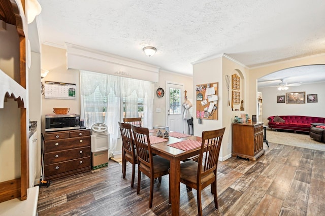 dining area featuring dark hardwood / wood-style floors, ceiling fan, crown molding, and a textured ceiling