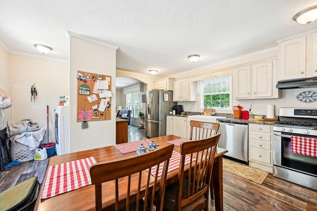 kitchen with sink, stainless steel appliances, dark hardwood / wood-style floors, washer / dryer, and ornamental molding