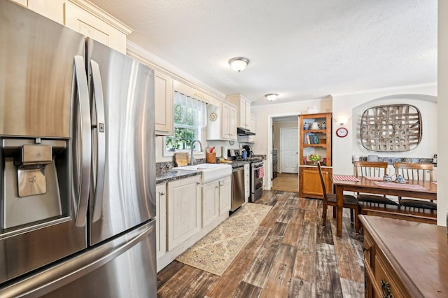 kitchen featuring dark wood-type flooring, sink, dark stone countertops, a textured ceiling, and stainless steel appliances