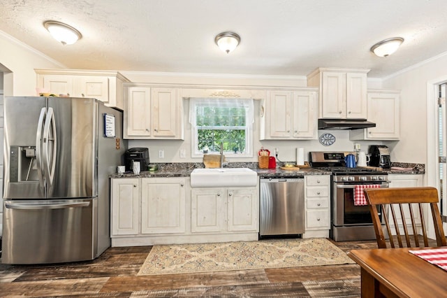 kitchen with ornamental molding, a textured ceiling, stainless steel appliances, dark wood-type flooring, and sink