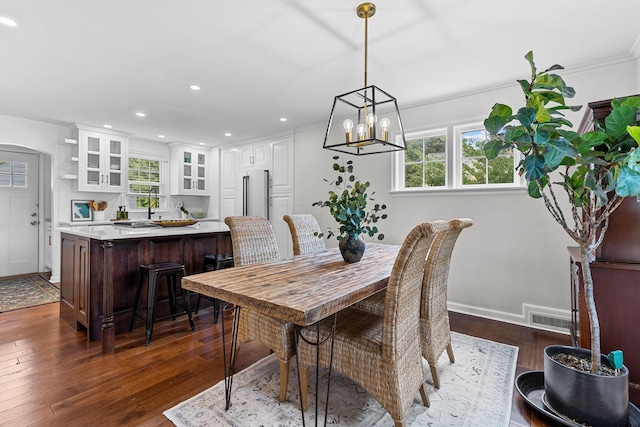 dining space with crown molding, dark hardwood / wood-style floors, and a notable chandelier