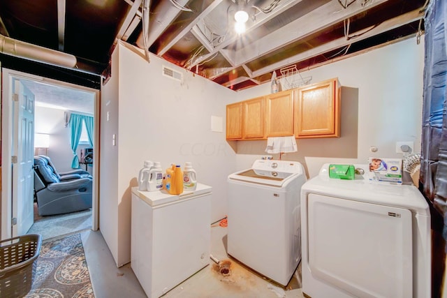 clothes washing area featuring separate washer and dryer and cabinets