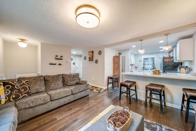 living room with a textured ceiling and dark hardwood / wood-style floors