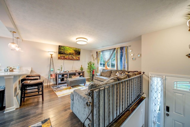 living room with a textured ceiling and dark hardwood / wood-style floors