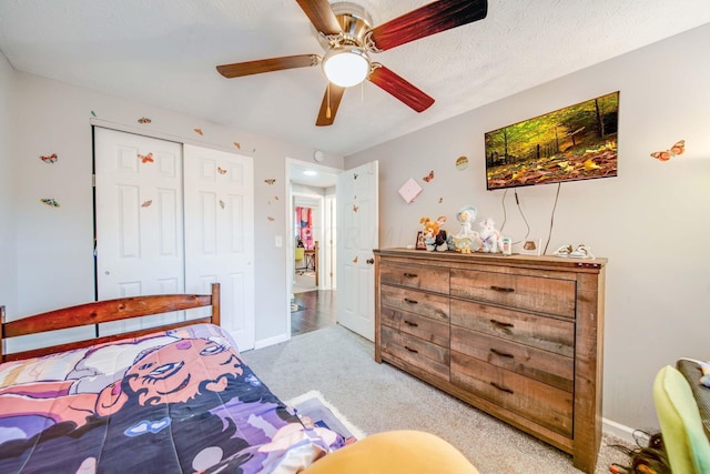 bedroom with a textured ceiling, ceiling fan, light carpet, and a closet