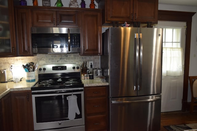 kitchen with backsplash, dark hardwood / wood-style floors, light stone counters, and stainless steel appliances