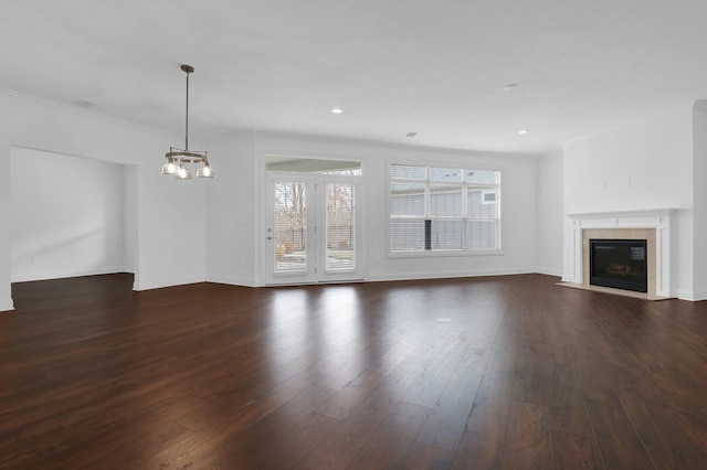 unfurnished living room with dark wood-type flooring, ornamental molding, and a chandelier