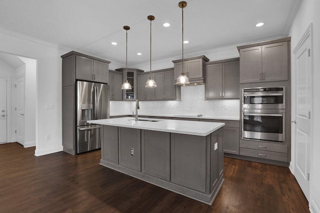 kitchen featuring pendant lighting, an island with sink, sink, gray cabinetry, and stainless steel appliances