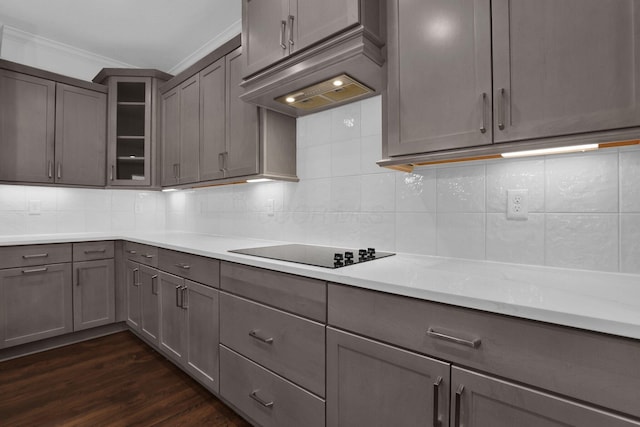 kitchen with crown molding, backsplash, dark hardwood / wood-style floors, light stone counters, and black electric cooktop