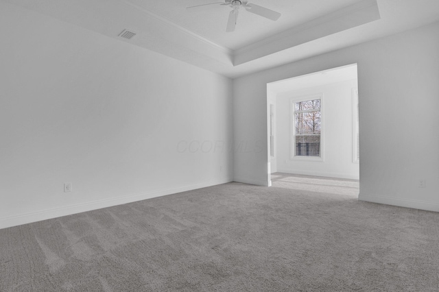 carpeted spare room featuring a raised ceiling, crown molding, and ceiling fan