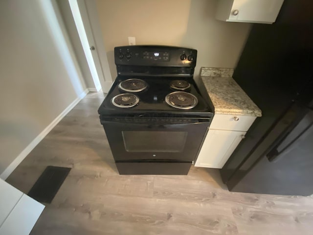 kitchen with white cabinets, light hardwood / wood-style flooring, light stone countertops, and black appliances