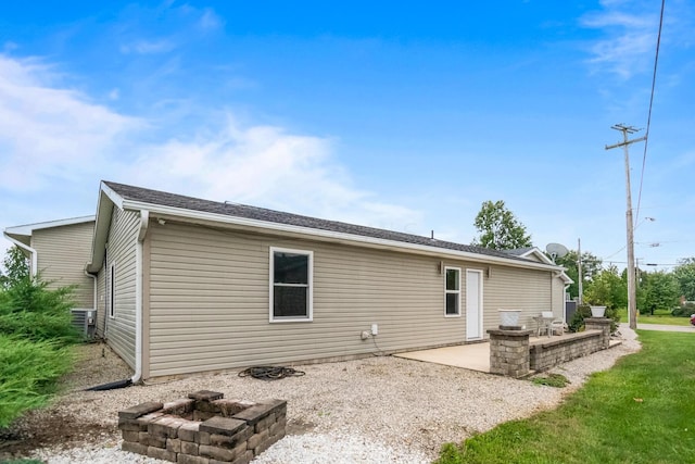 rear view of property featuring central AC unit, a patio area, and an outdoor fire pit