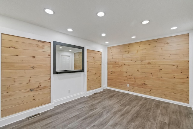 spare room featuring wood walls and wood-type flooring