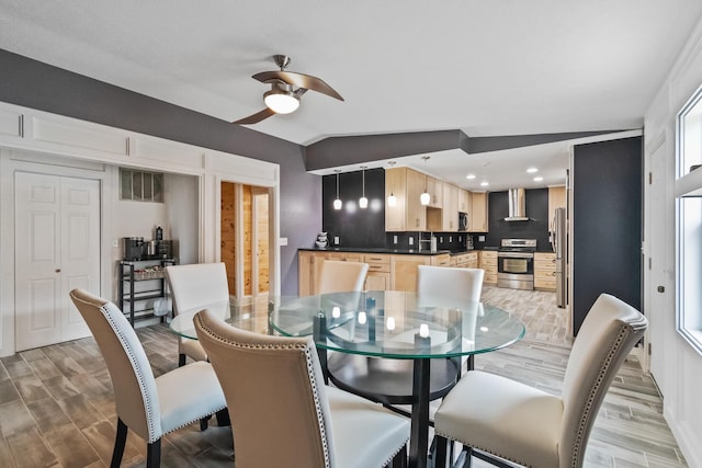 dining area featuring ceiling fan, lofted ceiling, and light hardwood / wood-style flooring