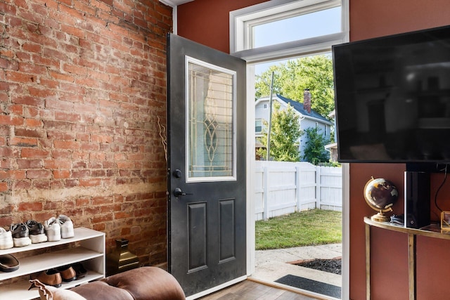 doorway to outside featuring brick wall and hardwood / wood-style flooring