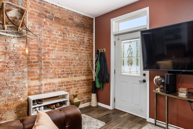 entrance foyer with dark hardwood / wood-style flooring and brick wall