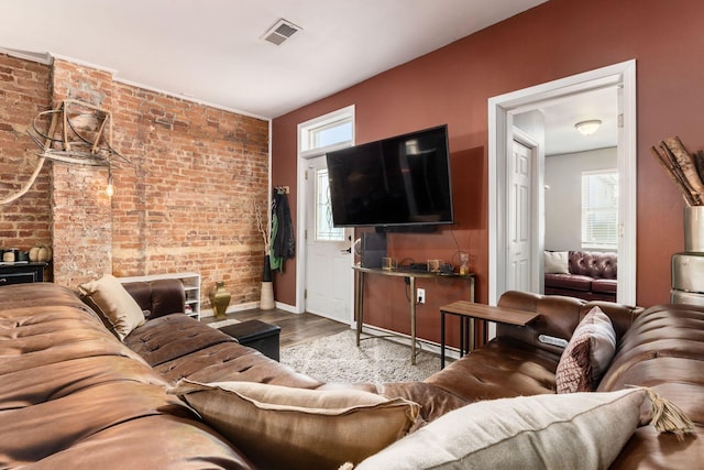 living room with plenty of natural light, light wood-type flooring, and brick wall