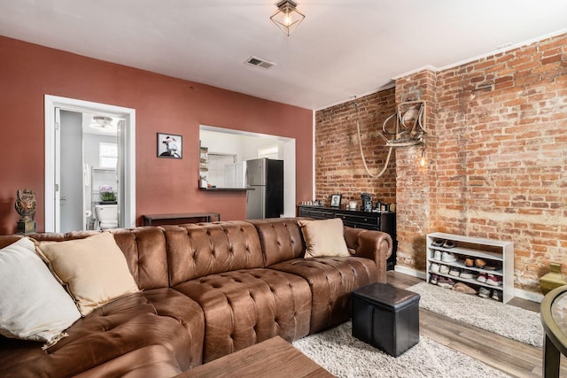 living room featuring hardwood / wood-style floors and brick wall