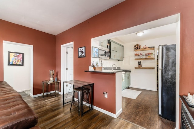 kitchen featuring dark hardwood / wood-style floors, a breakfast bar area, stainless steel refrigerator, and green cabinetry