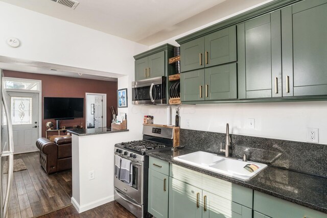 kitchen with sink, stainless steel appliances, green cabinets, dark hardwood / wood-style floors, and dark stone countertops