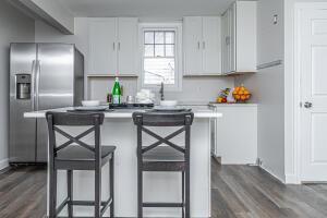 kitchen featuring a kitchen breakfast bar, stainless steel refrigerator with ice dispenser, a kitchen island, dark hardwood / wood-style flooring, and white cabinetry